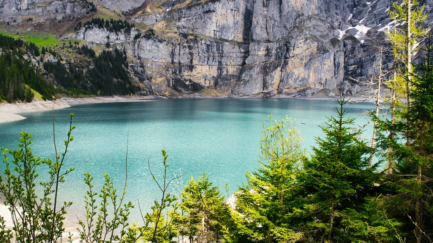 Blue Oeschinen Lake below limestone cliffs and green alpine slopes
