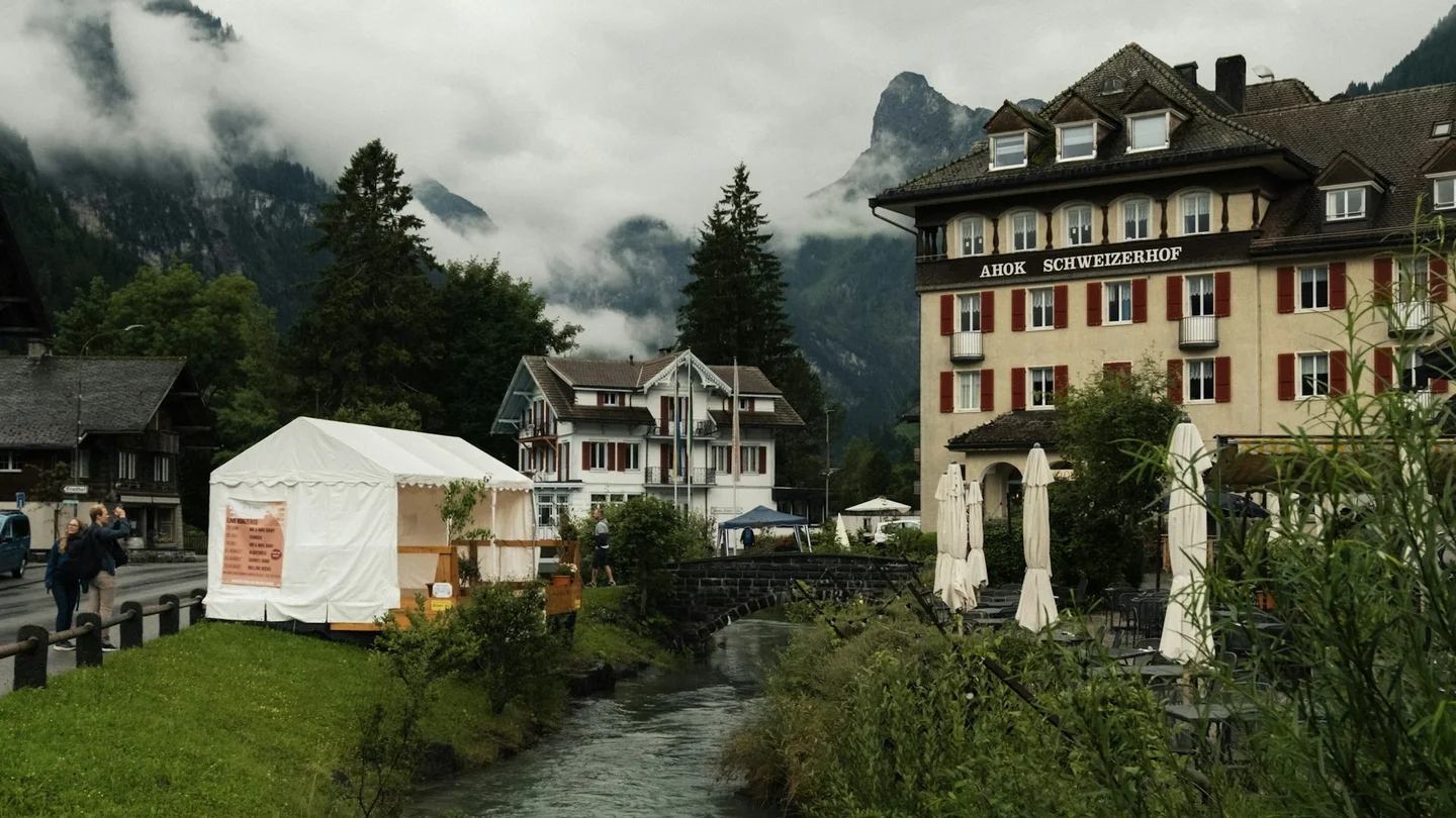 Buildings and a river in Kandersteg beneath misty slopes